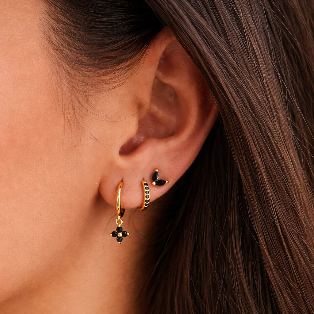 A model wears the New Perspective SET in black onyx, layering a marquise stud, pavé hoop, and flower dangle hoop along the ear.