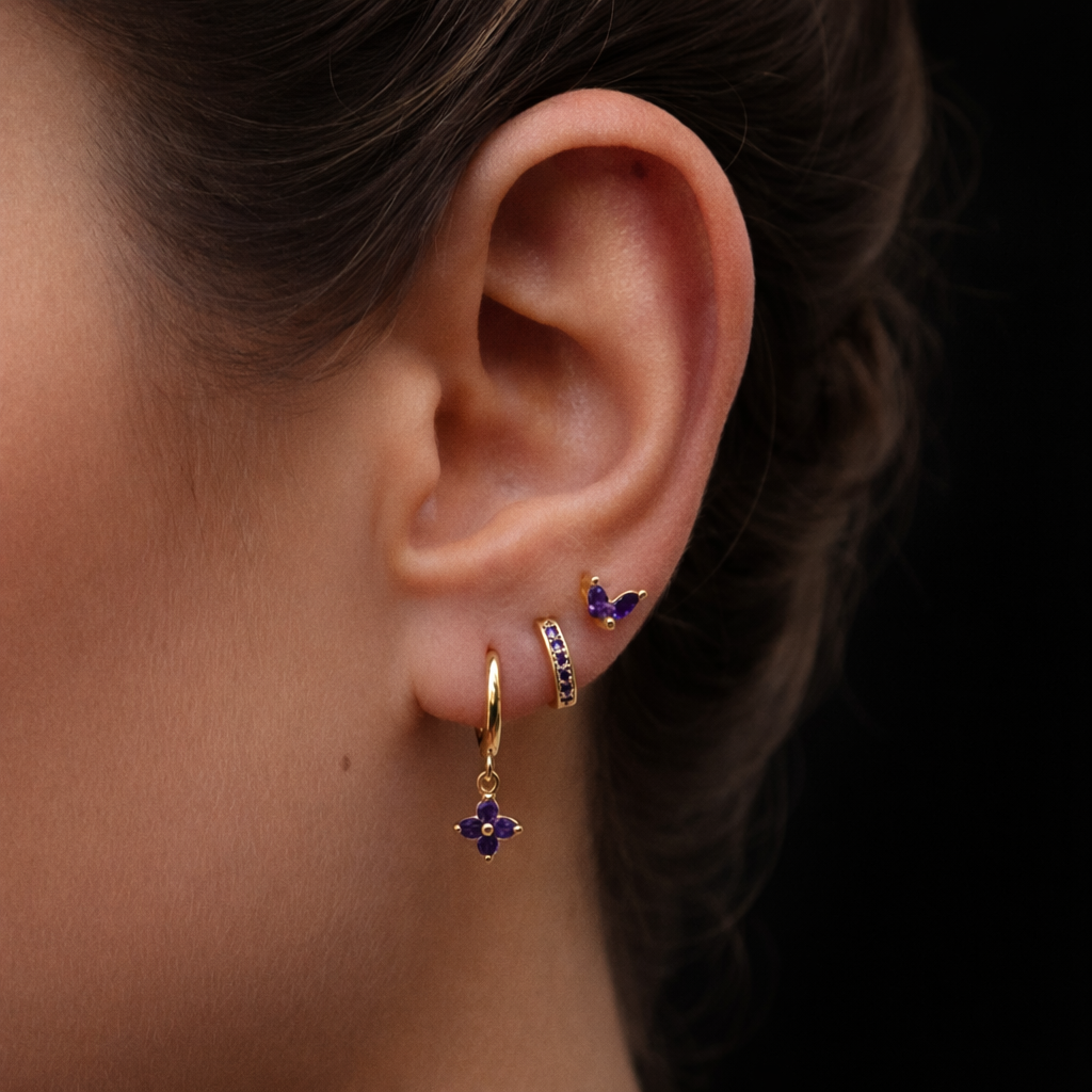 A model wears the New Perspective SET in amethyst purple, combining a marquise stud, pavé hoop, and flower dangle hoop along the ear.