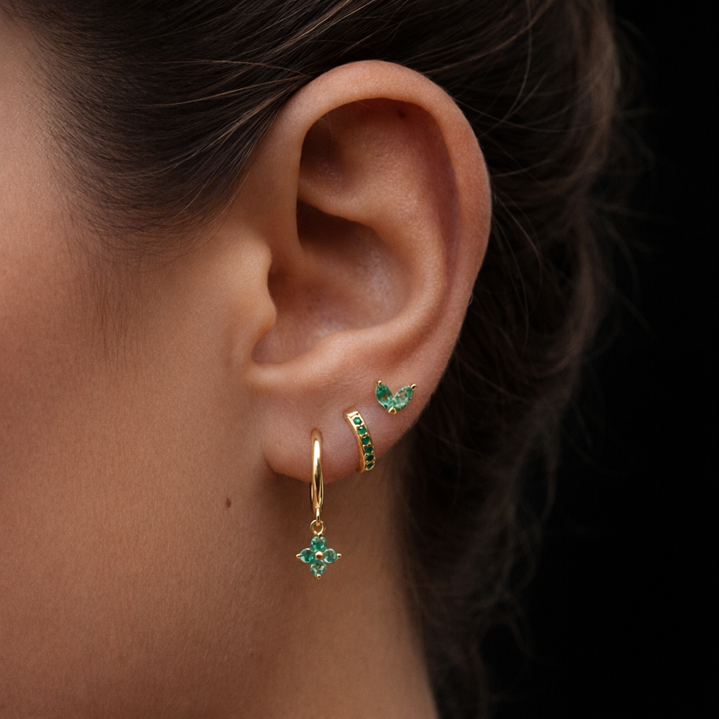 A model wears the New Perspective SET in emerald green, pairing a marquise stud, pavé hoop, and flower dangle hoop along the ear.