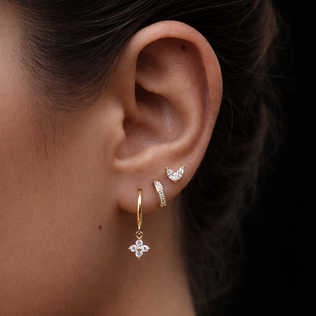 A model wears the New Perspective SET in clear crystal, layering a marquise stud, pavé hoop, and flower dangle hoop along the ear.