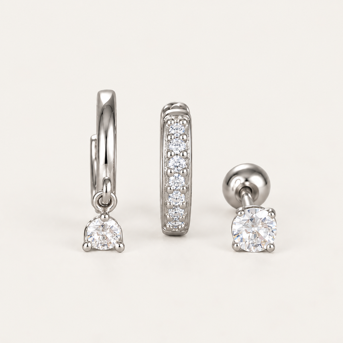 The Folie à Trois Noor SET in silver: a hoop with a dangling round crystal, a pavé bar hoop and a round bezel stud.