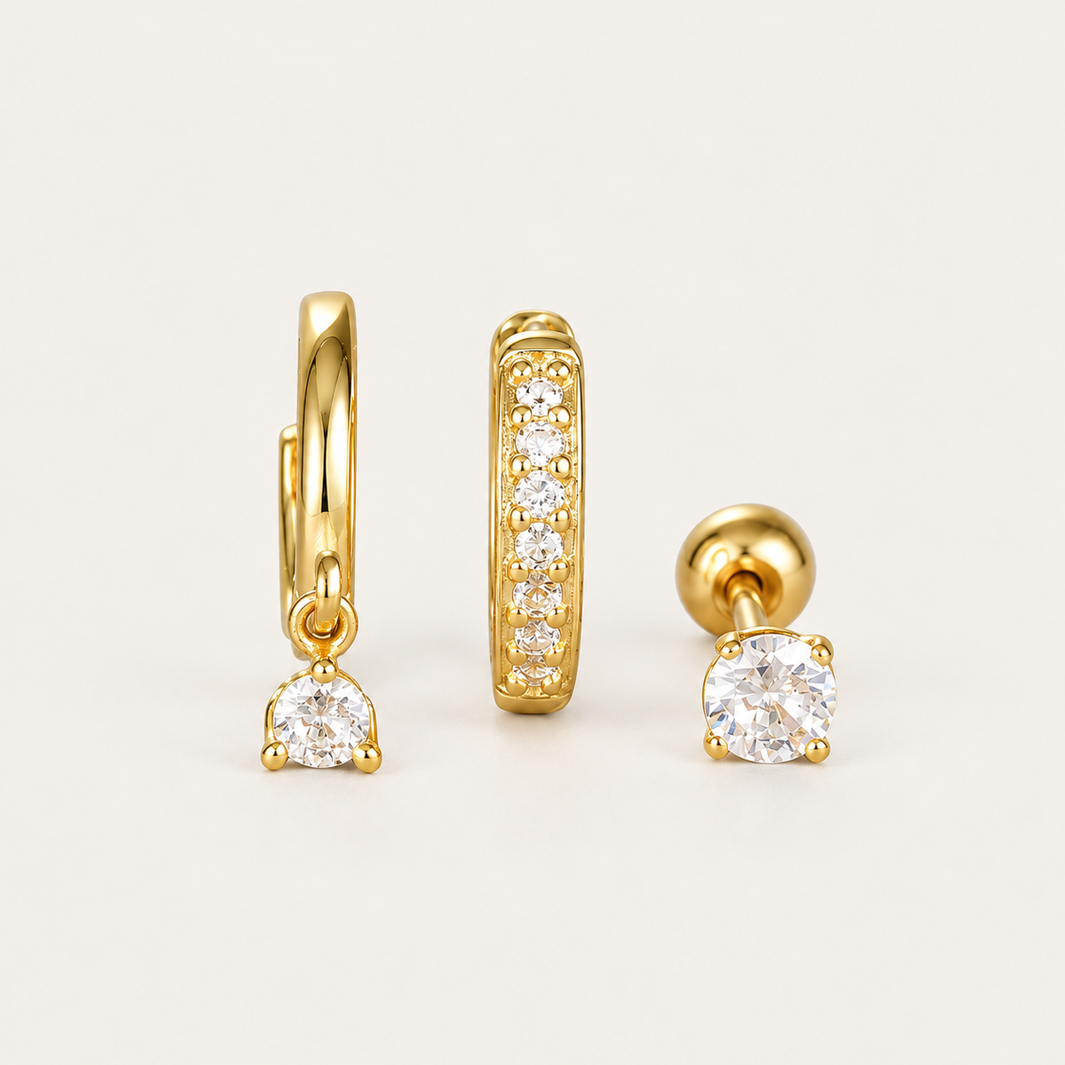 Three gold Folie à Trois Noor SET pieces: a hoop with a dangling round crystal, a pavé bar hoop and a round bezel stud.