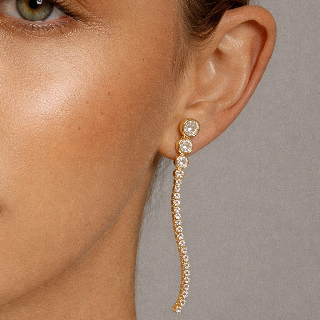 Worn close up in gold, Odette Earrings curve along the ear with bezel-set crystals fading into a sparkling pave tail.