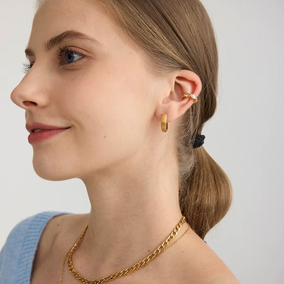 Overdrive ear cuff worn on the cartilage in profile, paired with a ribbed gold hoop and a layered chain necklace.