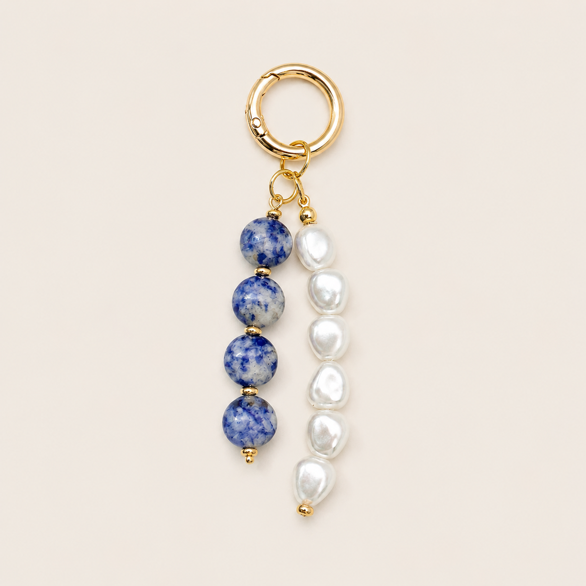 Folie à Trois Perla BAG CHARM with blue-and-white speckled beads and baroque pearl strands on a gold hoop clasp.