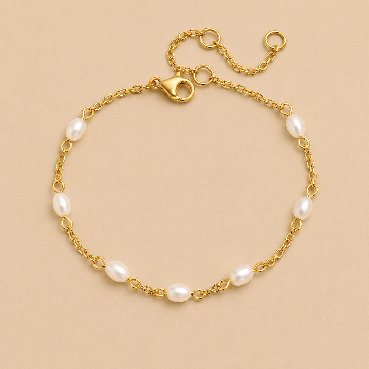 Perle BRACELET in gold with small oval freshwater pearls spaced along a delicate chain, shown flat on a beige background.