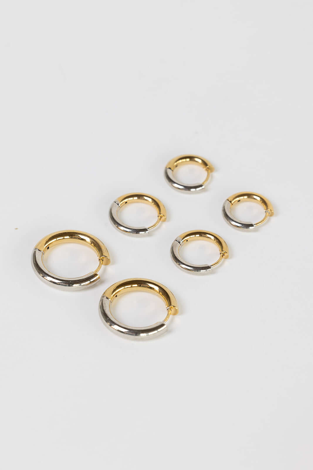 Radiant Bliss Earrings show six chunky tube hoops mixing gold and silver tones on a plain white background.