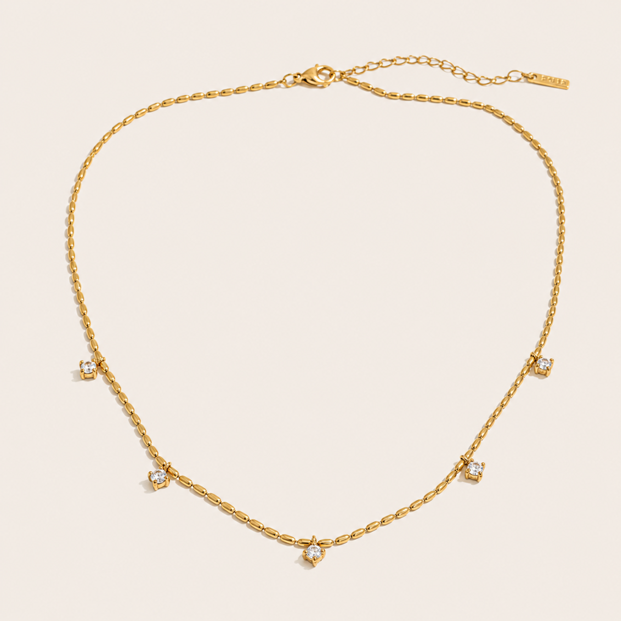 Gold station necklace with five round white zirconia charms spaced along a fine beaded chain — Folie à Trois Reverie NECKLACE.