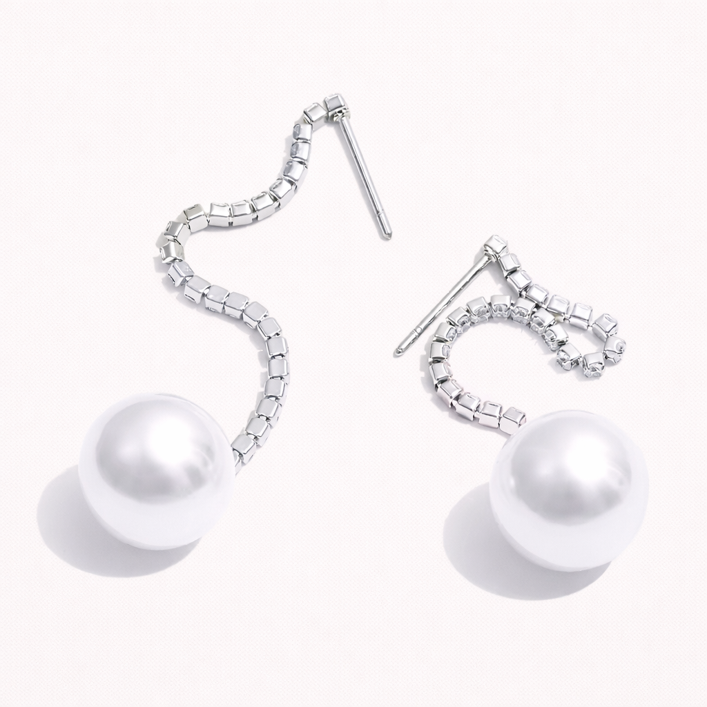 Rhea Earrings in a silver-tone finish, the wavy crystal-lined chain curling down to a glossy white pearl at the end.