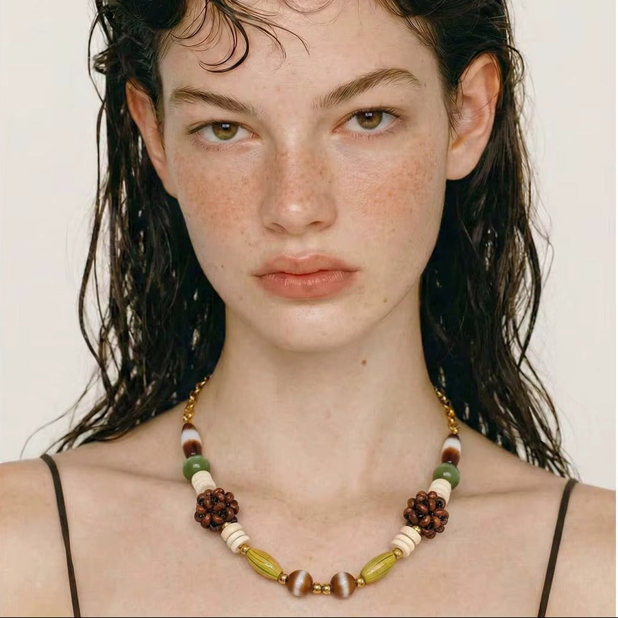 The Rio NECKLACE worn close-up in a straight-on portrait, the model's wet hair falling over her shoulders and thin straps.