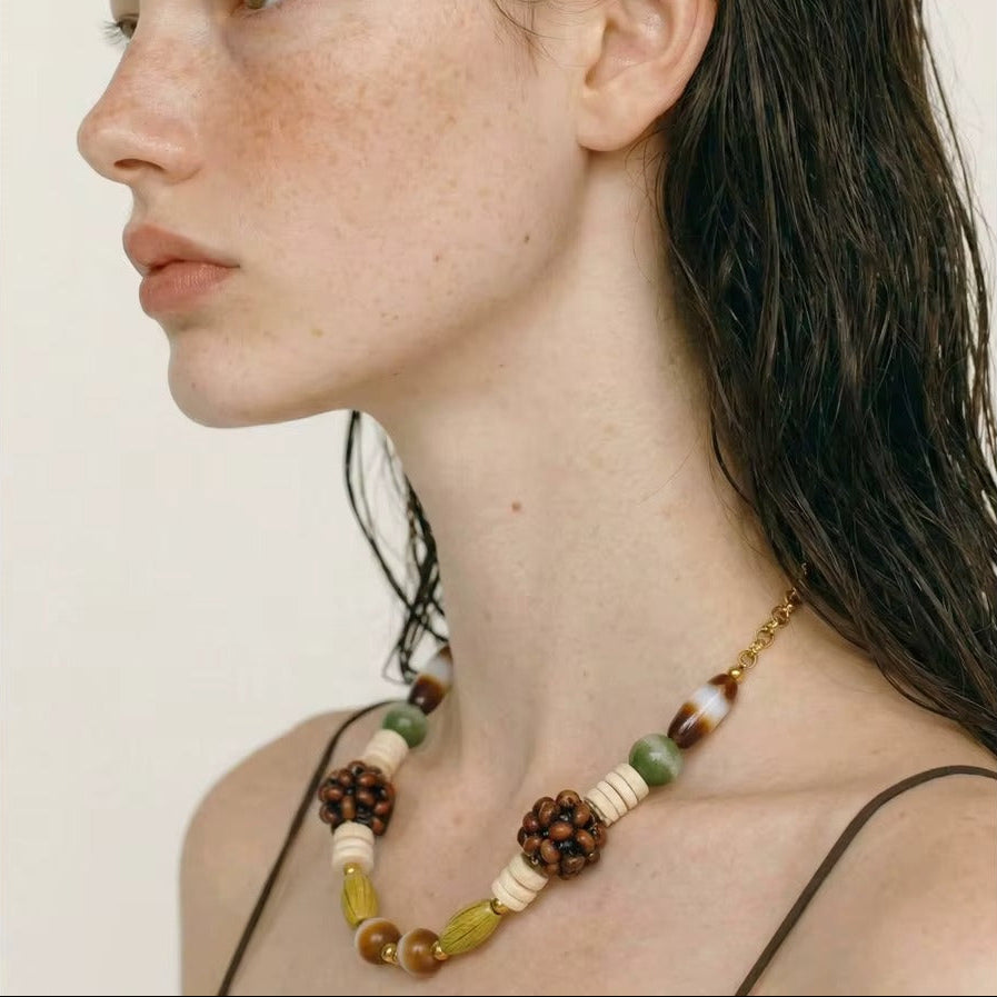 The Rio NECKLACE worn in profile, the model's wet hair swept back to reveal the beaded strand along her collarbone.
