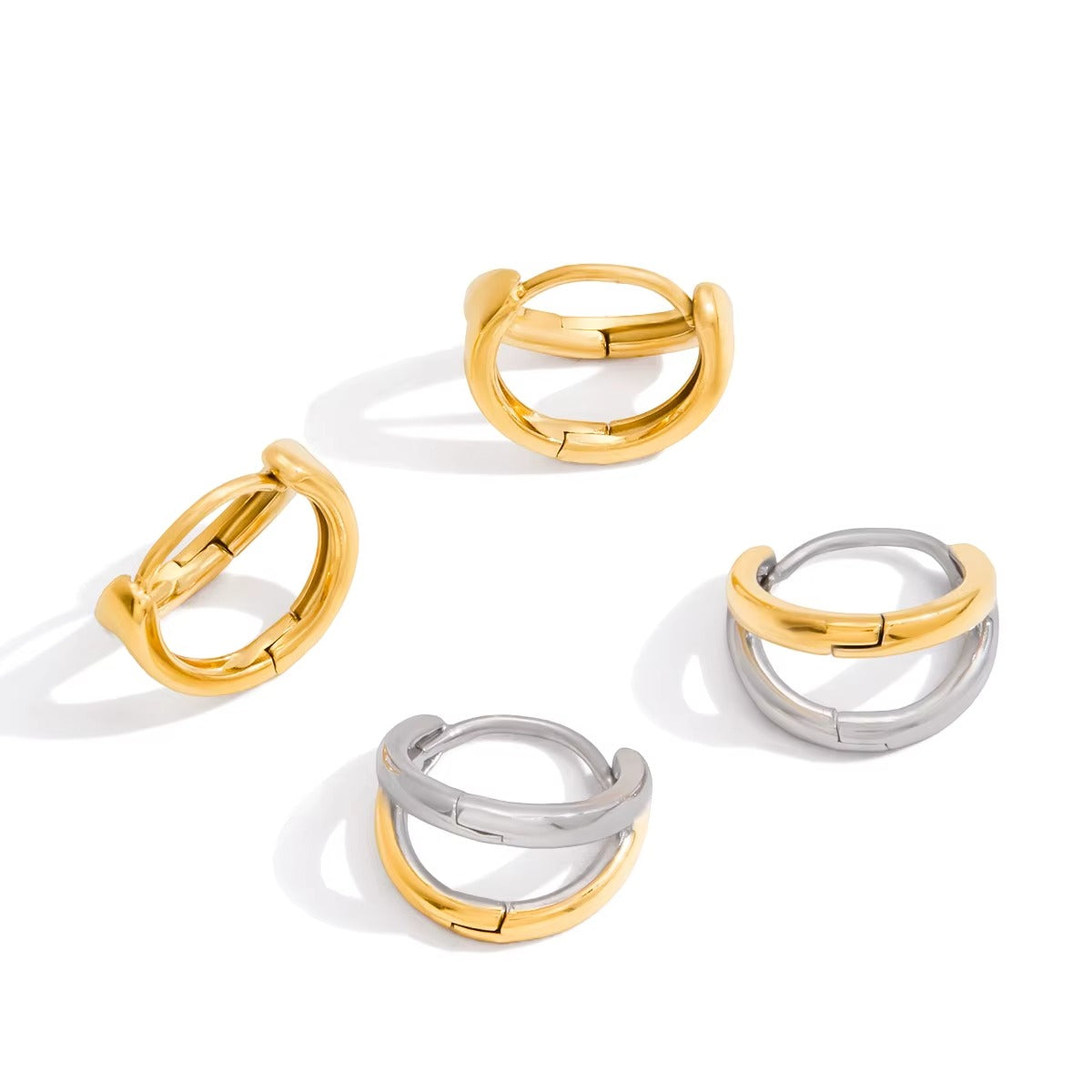 Four Roadtrip Earrings hoops laid flat, two in gold and two in mixed gold-and-silver, showing the double-band design.