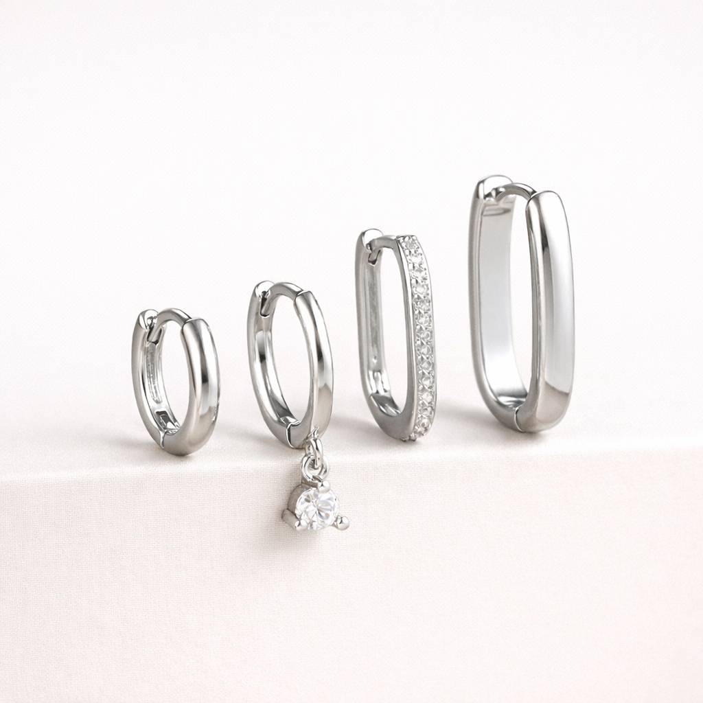 The Sabrina SET is shown in a silver finish with clear crystals, pave-lined and dangling stones on two hoops.