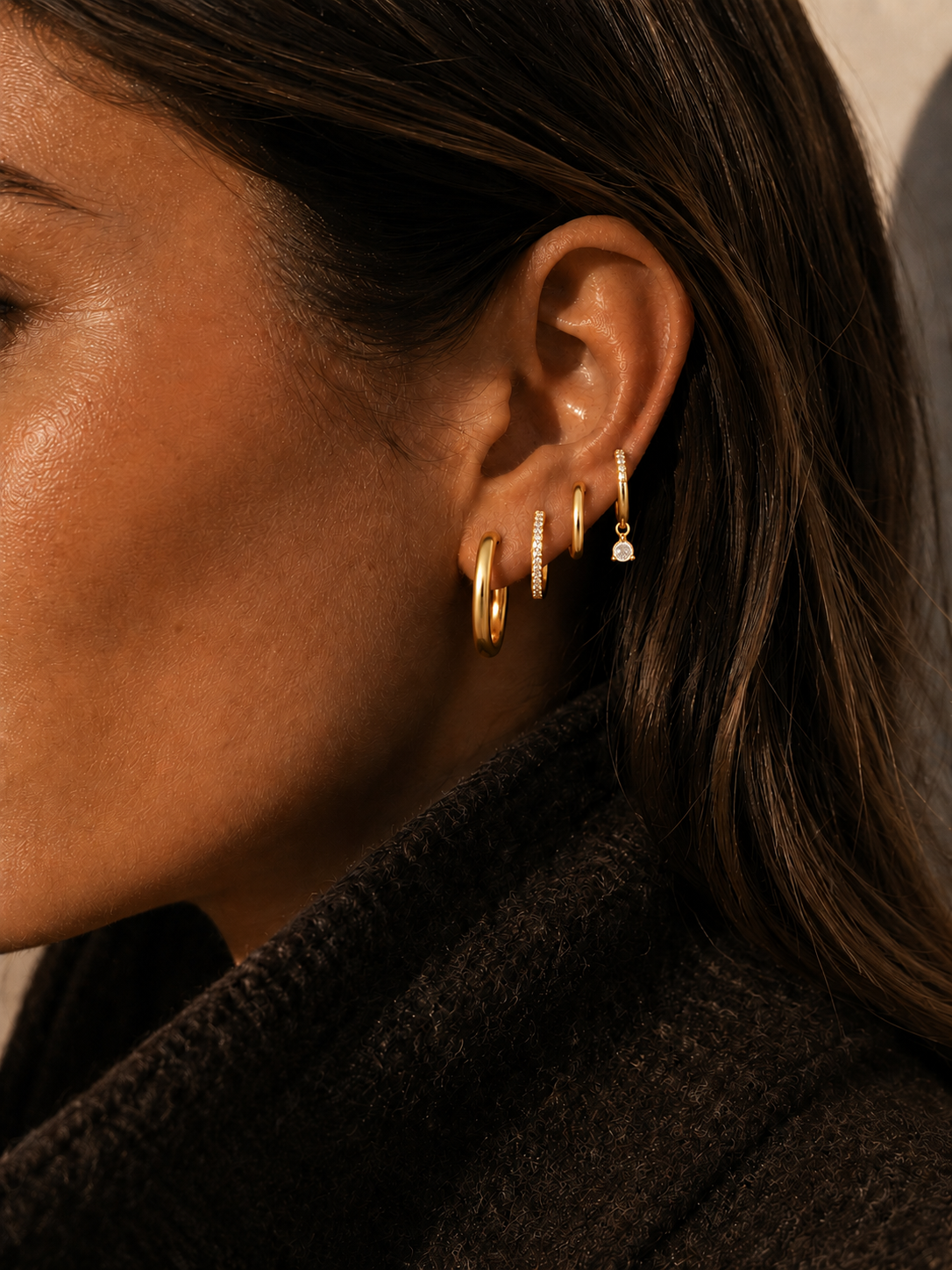 Model wears the Folie à Trois Sabrina SET, four graduating gold hoops with a small crystal drop stacked along the ear.