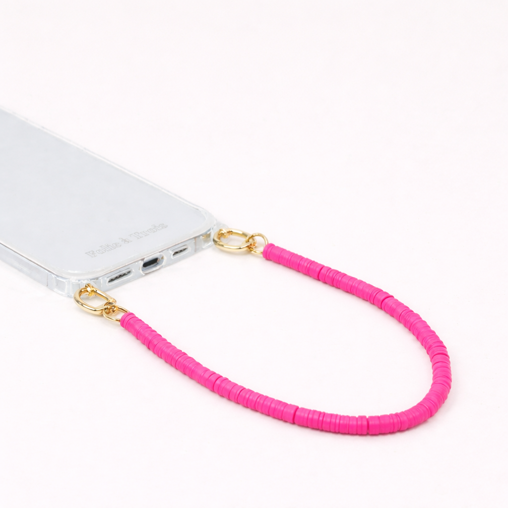 Hot pink heishi bead Scottie SHORT PHONE CORD clipped to a clear phone case with gold hardware.
