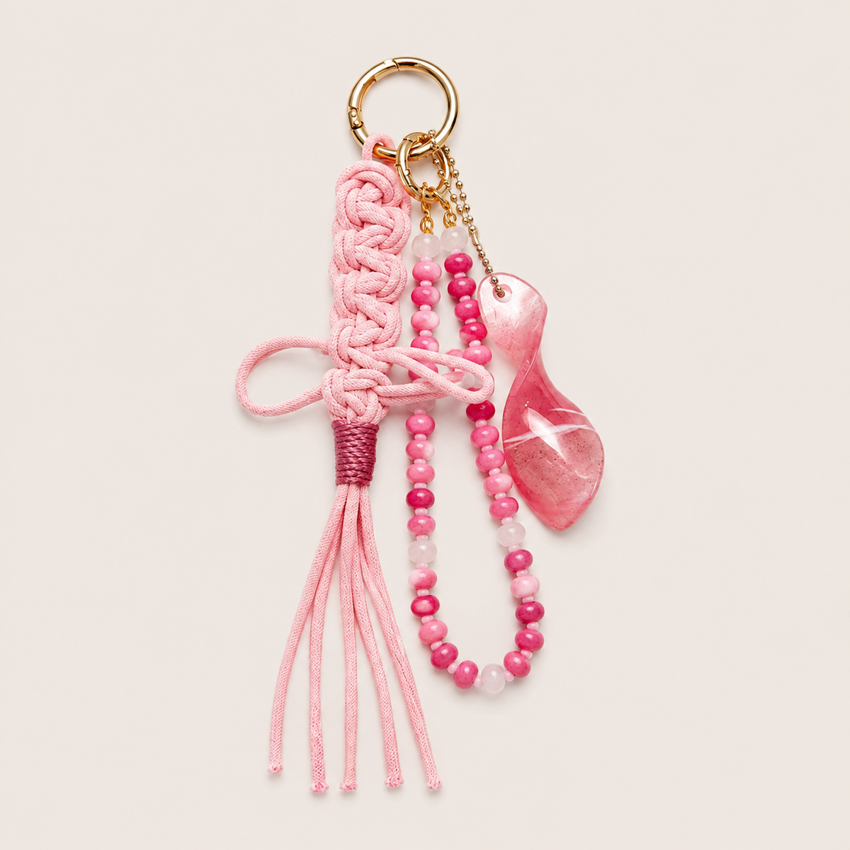 Folie à Trois Seraphina BAG CHARM, a pink macrame tassel with pink beaded strands and a pink glass drop charm on a gold clasp.