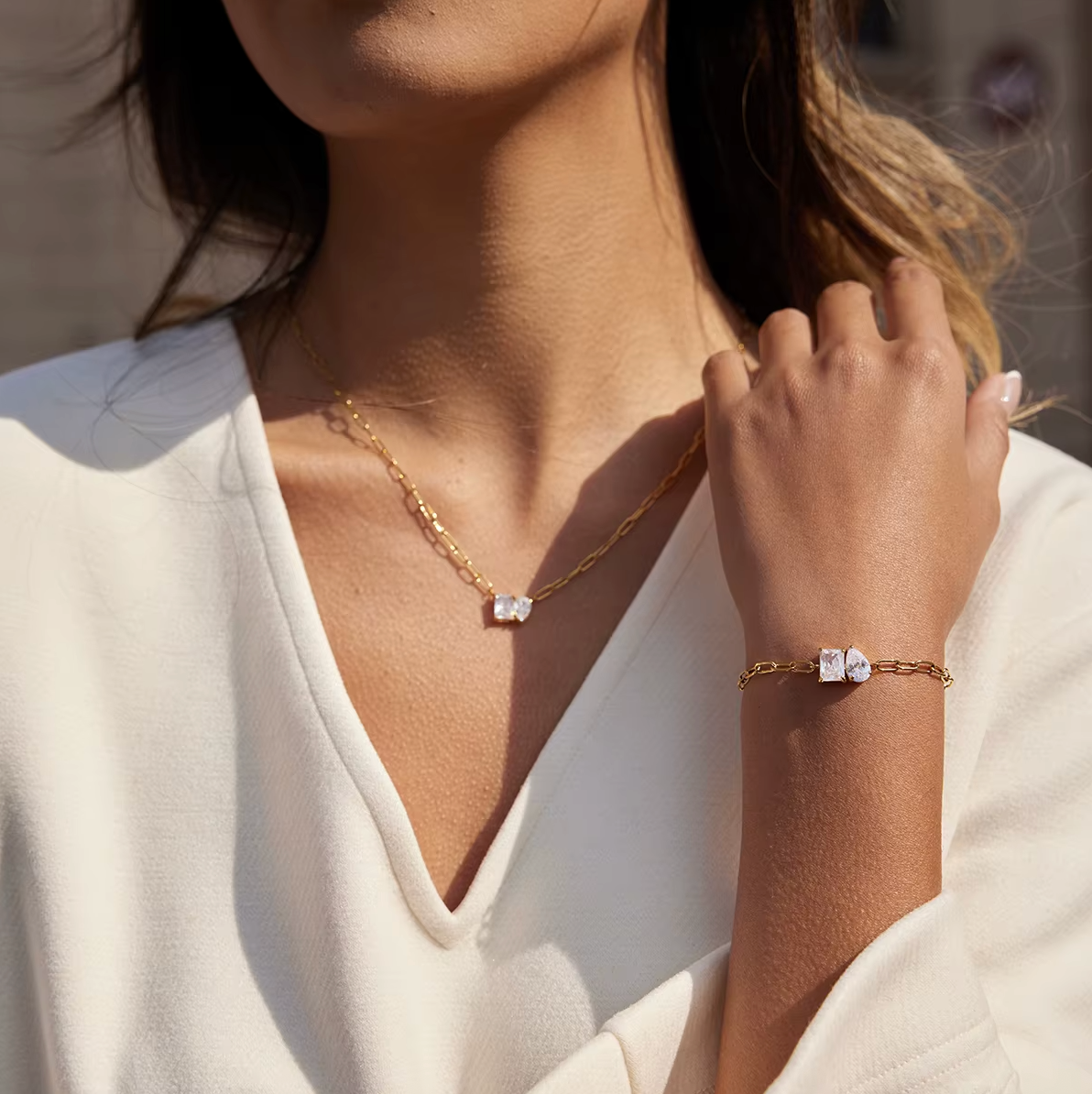 Sharp Halo BRACELET worn on the wrist with the matching necklace at the neck, cream top, outdoor bokeh background.