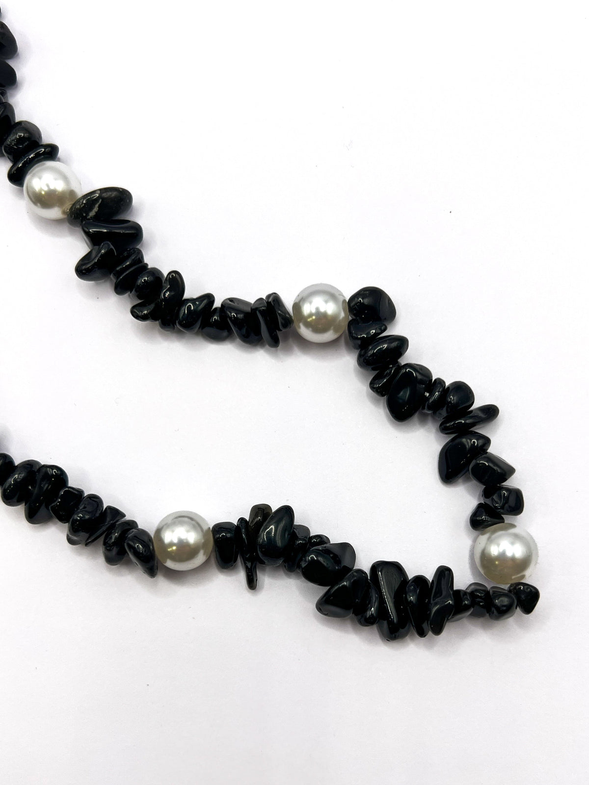 Close-up detail of a black beaded Shell Whisper SHORT PHONE STRAP, showing the chip beads and pearl accents.