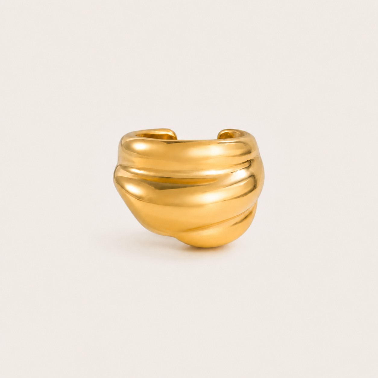 The Shockwave EAR CUFF in a studio flat lay, a chunky gold ear cuff with a ribbed, wave-like sculptural texture on a cream background.