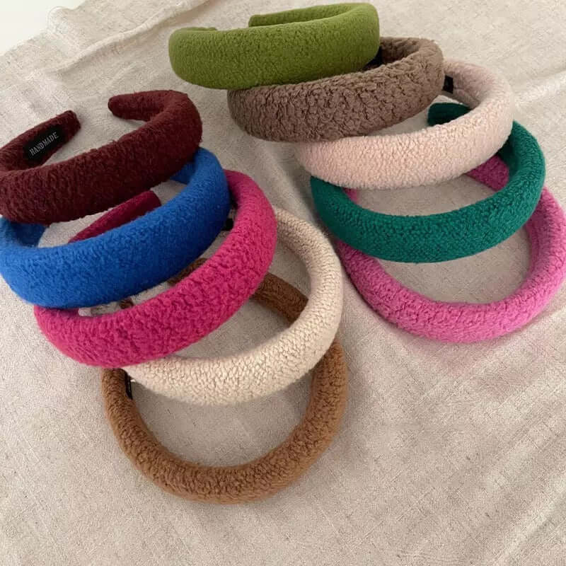 A group of ten Skylar HAIRBAND boucle padded headbands in green, taupe, cream, teal, pink, burgundy, blue and camel laid on linen.