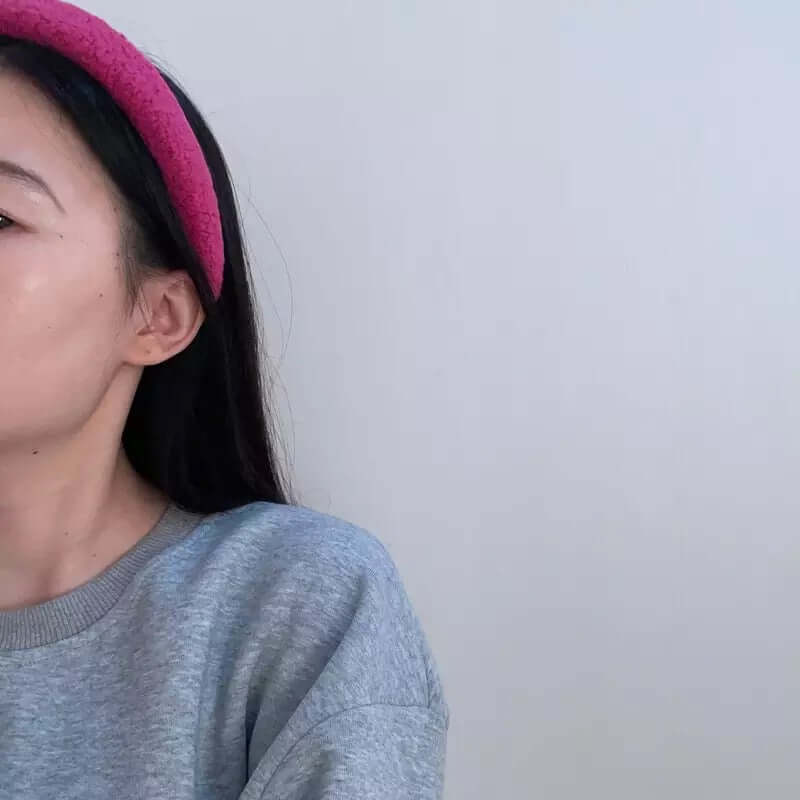 Profile shot of a young woman wearing a magenta pink boucle padded Skylar HAIRBAND.