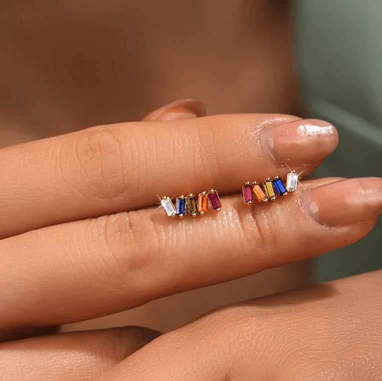 Held up close, Solara Earrings reveal their row of five baguette-cut stones in a rainbow of colors on gold settings.