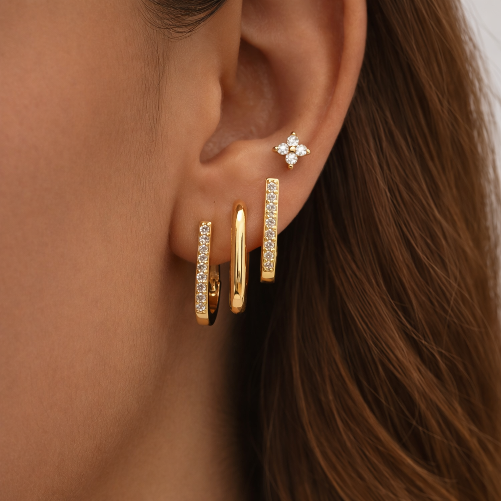 Sophia Set worn stacked along the ear, mixing a clover stud with three rectangular gold hoops of varying textures.