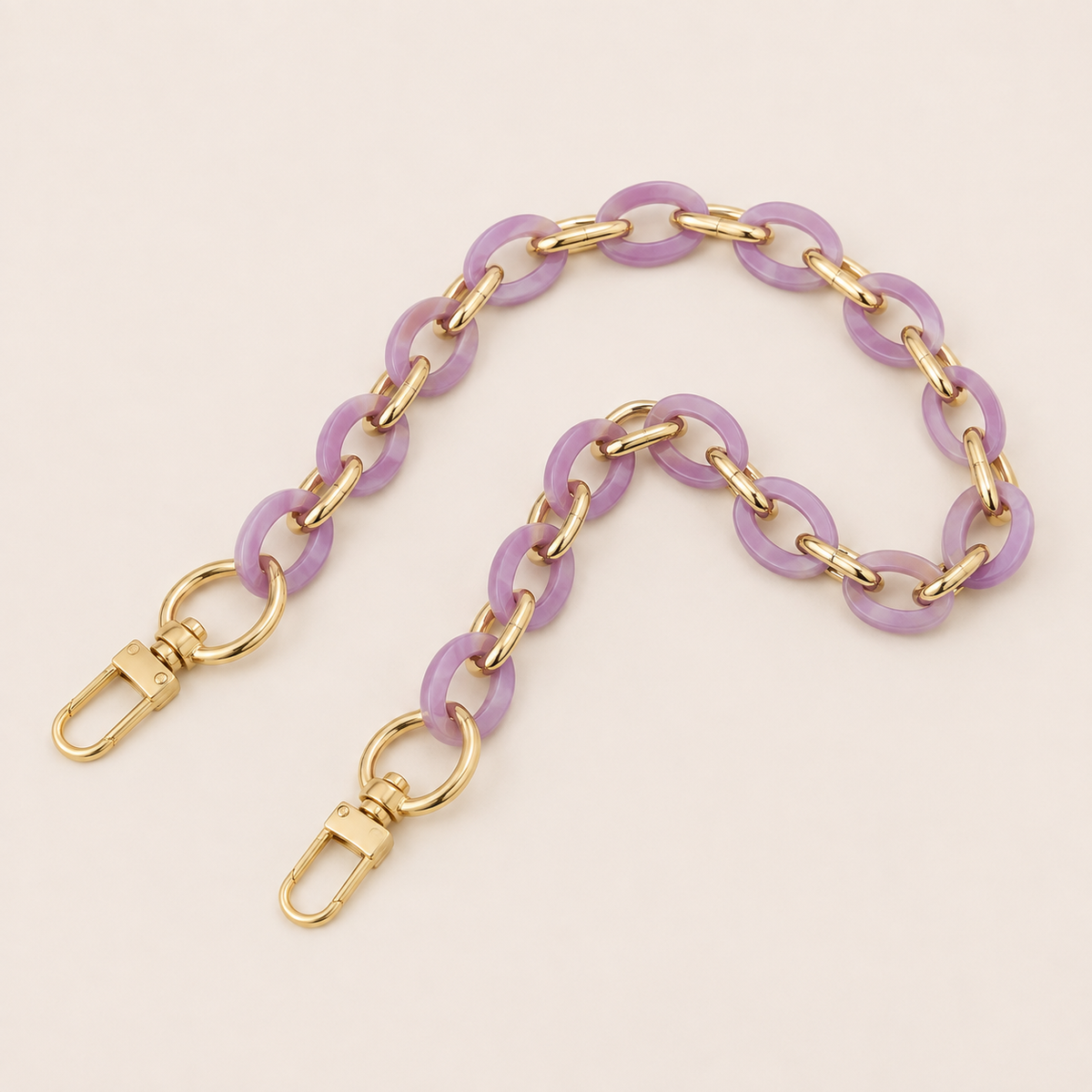 Folie à Trois Sorrel wholesale phone chain in lavender acetate rings with gold links and gold clasps, laid flat on a cream background.