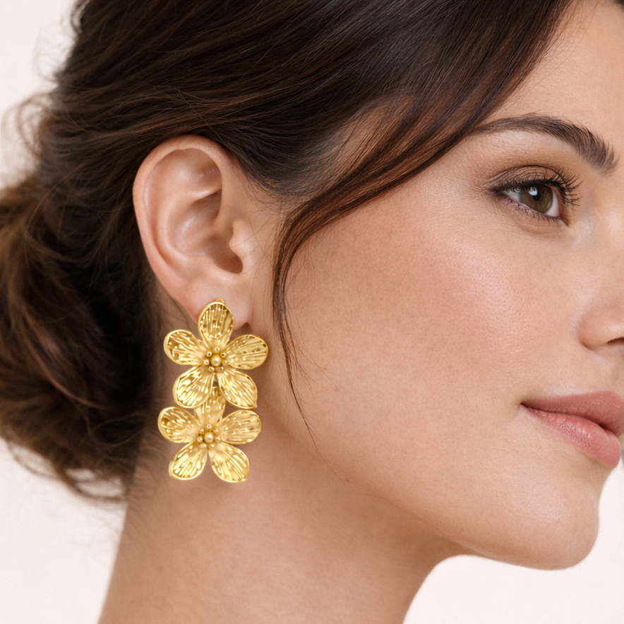 Worn on a model's ear, the gold Spring Bloom EARRINGS cascade with two ridged flower blooms in profile.