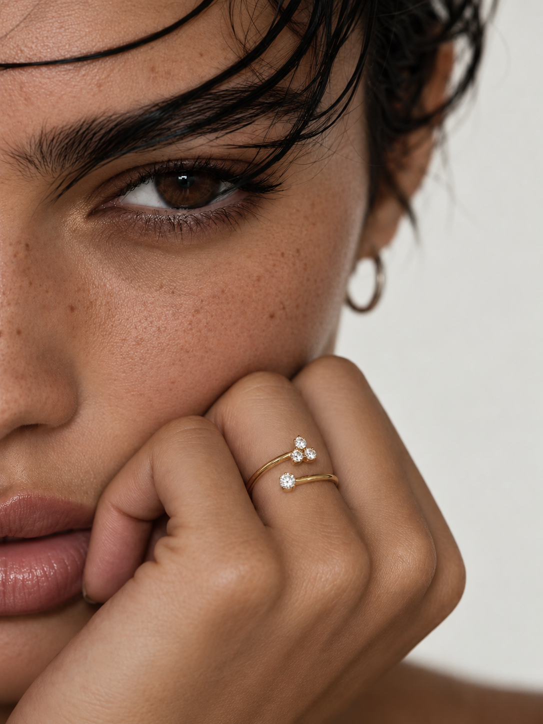 Close-up portrait of a freckled model resting her chin on her hand, wearing the fine gold Stella RING with zirconia — Folie à Trois