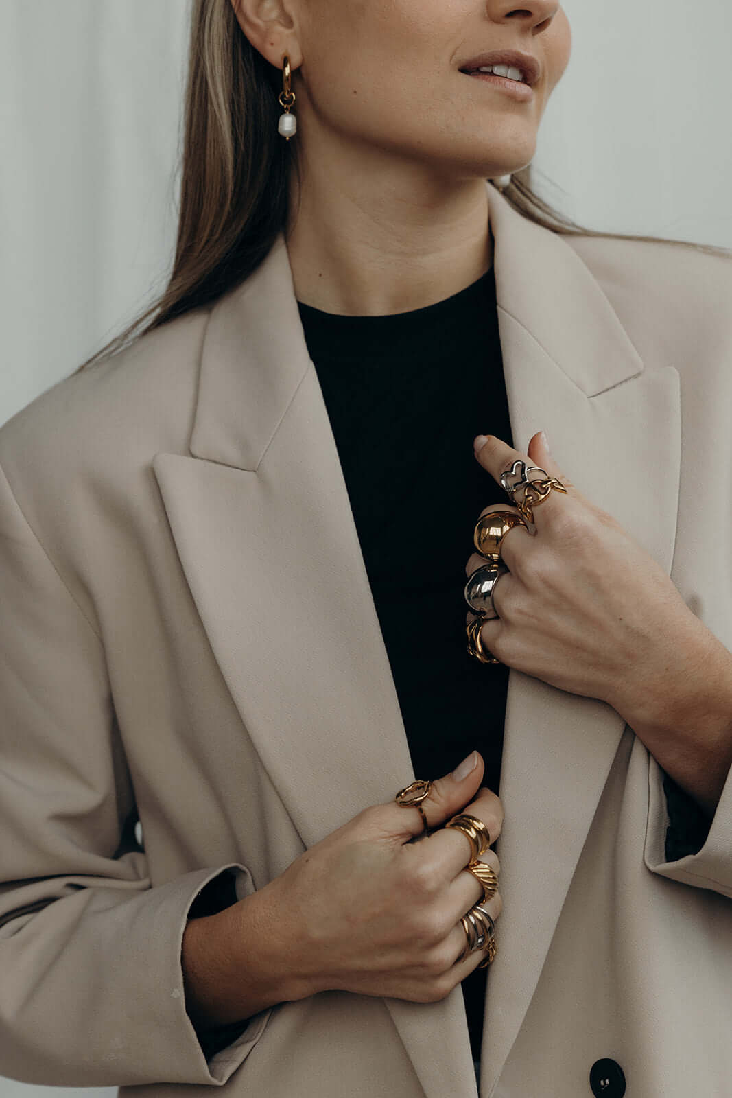 Woman in a beige blazer with both hands stacked in rings, including the silver heart-shaped Street Side RING.