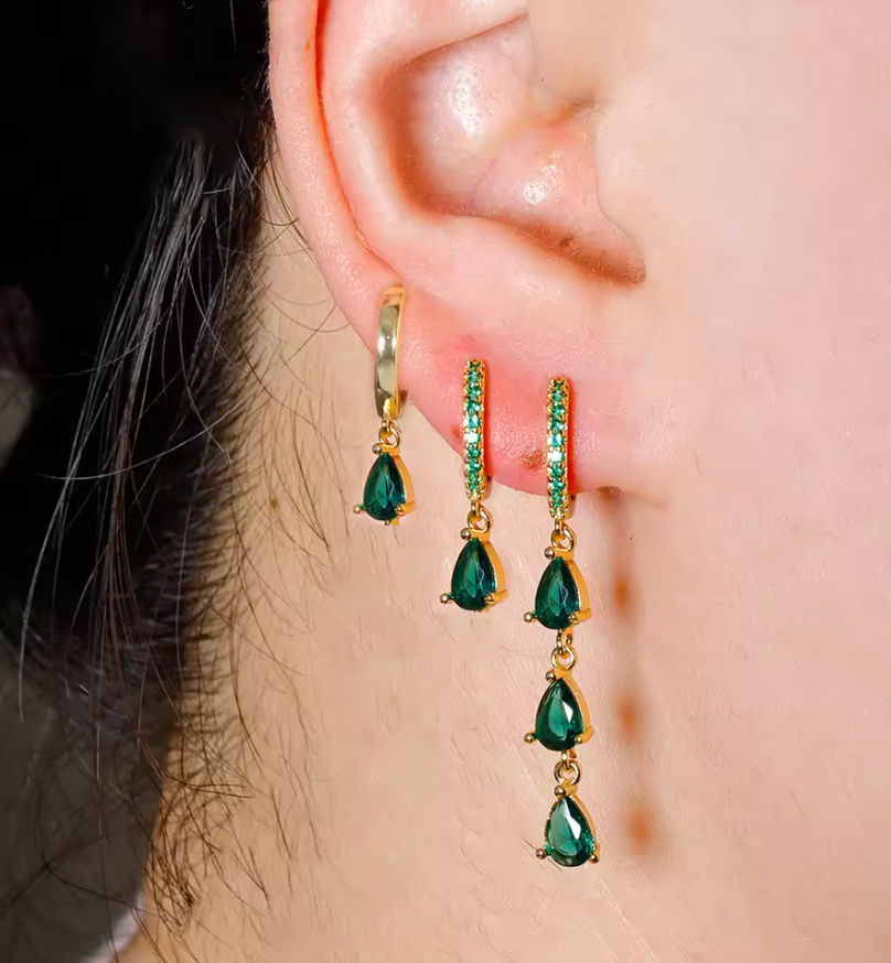 Waterfall Earrings worn close on the ear with green crystal drops cascading down beside a plain gold huggie hoop.