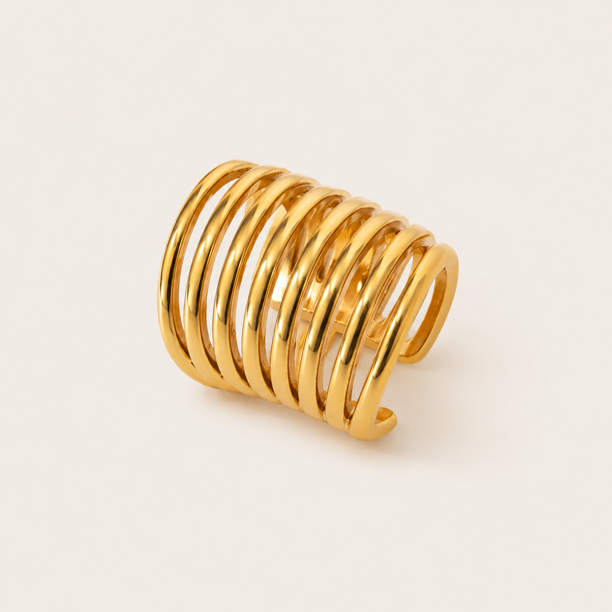 The Whitney EAR CUFF in a studio flat lay, a gold multi-band cuff made of several thin stacked rings, shown at an angle.