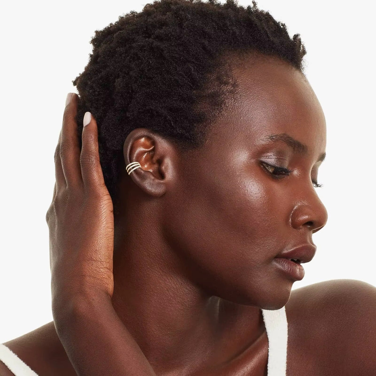 Wildcard Ear Cuff worn on the upper ear of a model with her hand raised to her hair, the pave crystal spiral wrapping the cartilage.