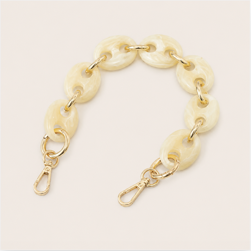 Folie à Trois Wilder short phone chain in ivory marbled puffed links with gold connectors, laid flat on a cream background.