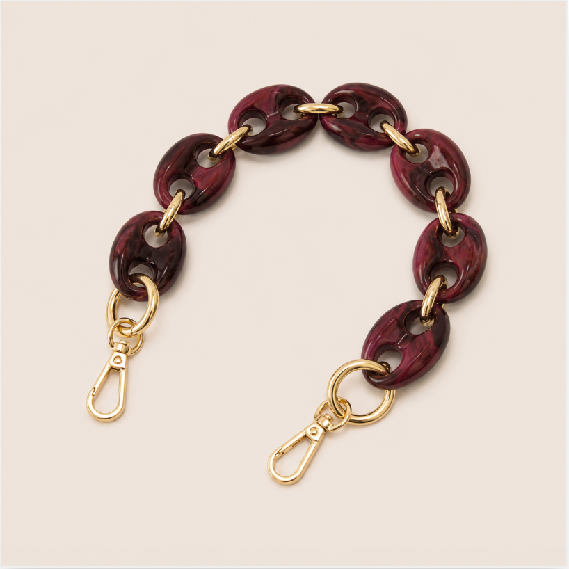 Folie à Trois Wilder short phone chain in wine red marbled puffed links with gold connectors, laid flat on a cream background.