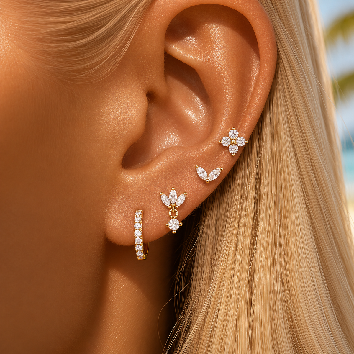 Close-up of a model's ear wearing the four-piece Willow SET gold earrings, including a flower stud, marquise studs, and a pave hoop.