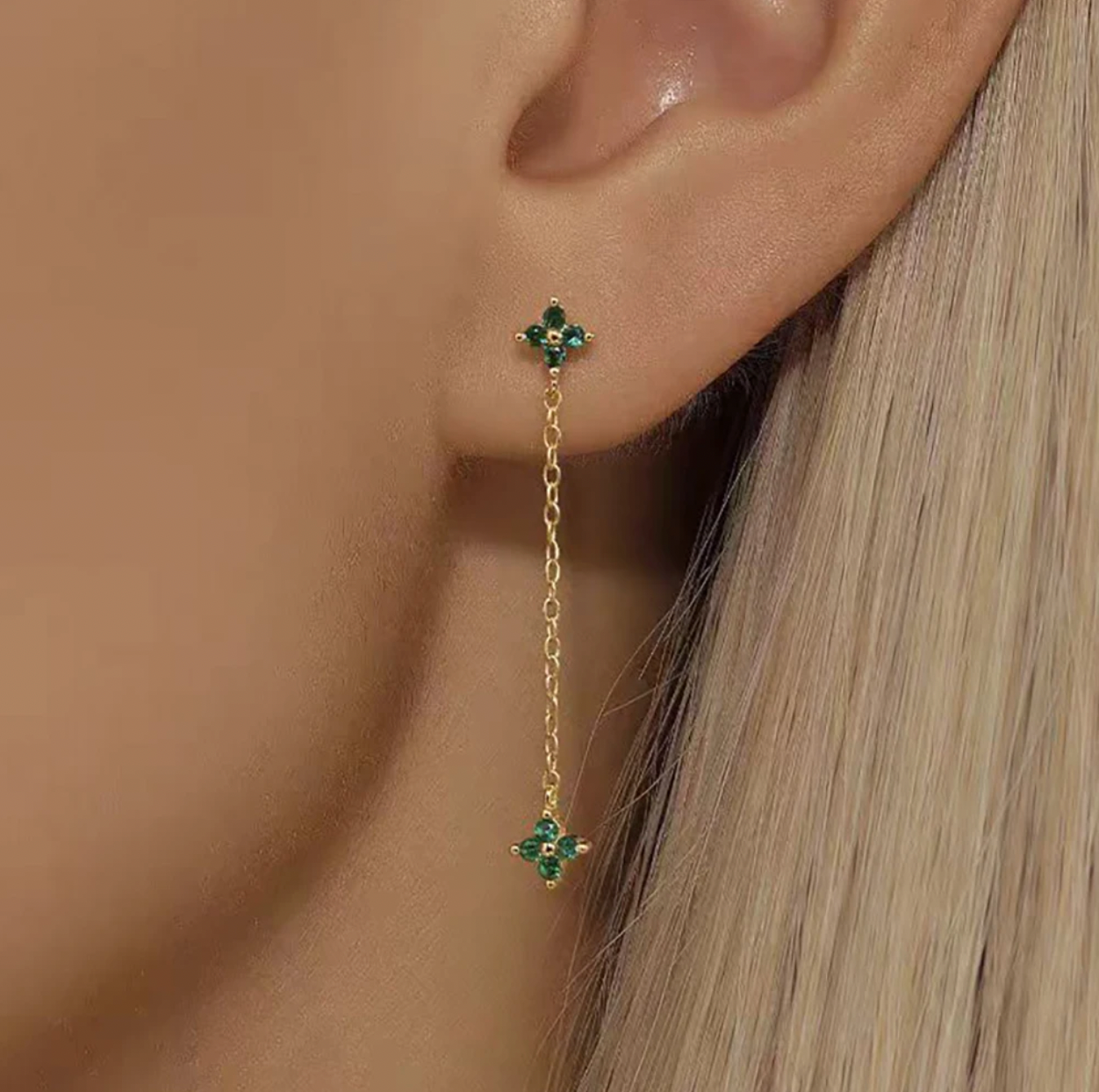 Zabbarra Earrings worn on the ear, the long gold chain draping from a clover stud down to a matching clover charm.