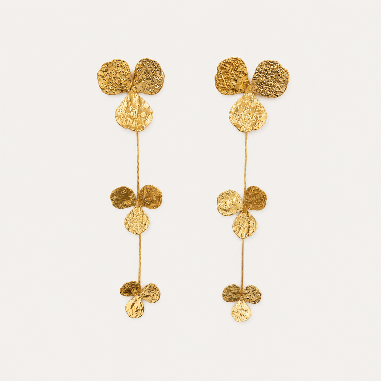 A pair of gold dangling earrings with textured circular leaf-like discs connected by thin vertical bars, shown on a plain light background.