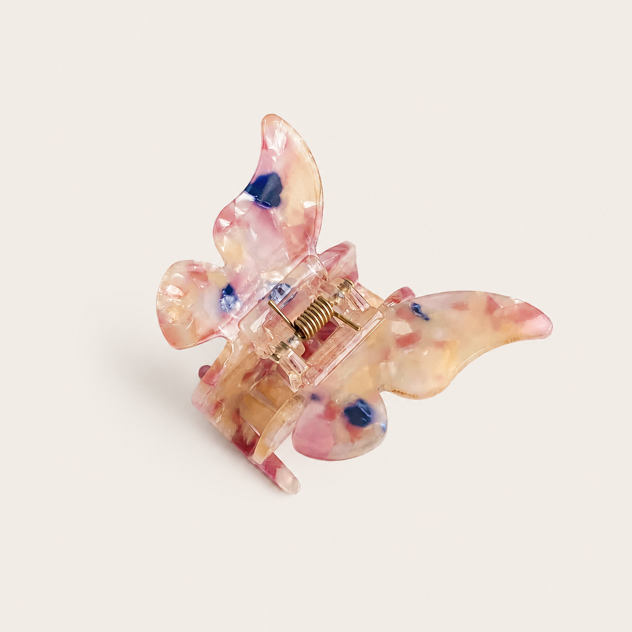A translucent butterfly-shaped hair claw clip with pink, red, and blue floral inclusions, shown on a light beige background.