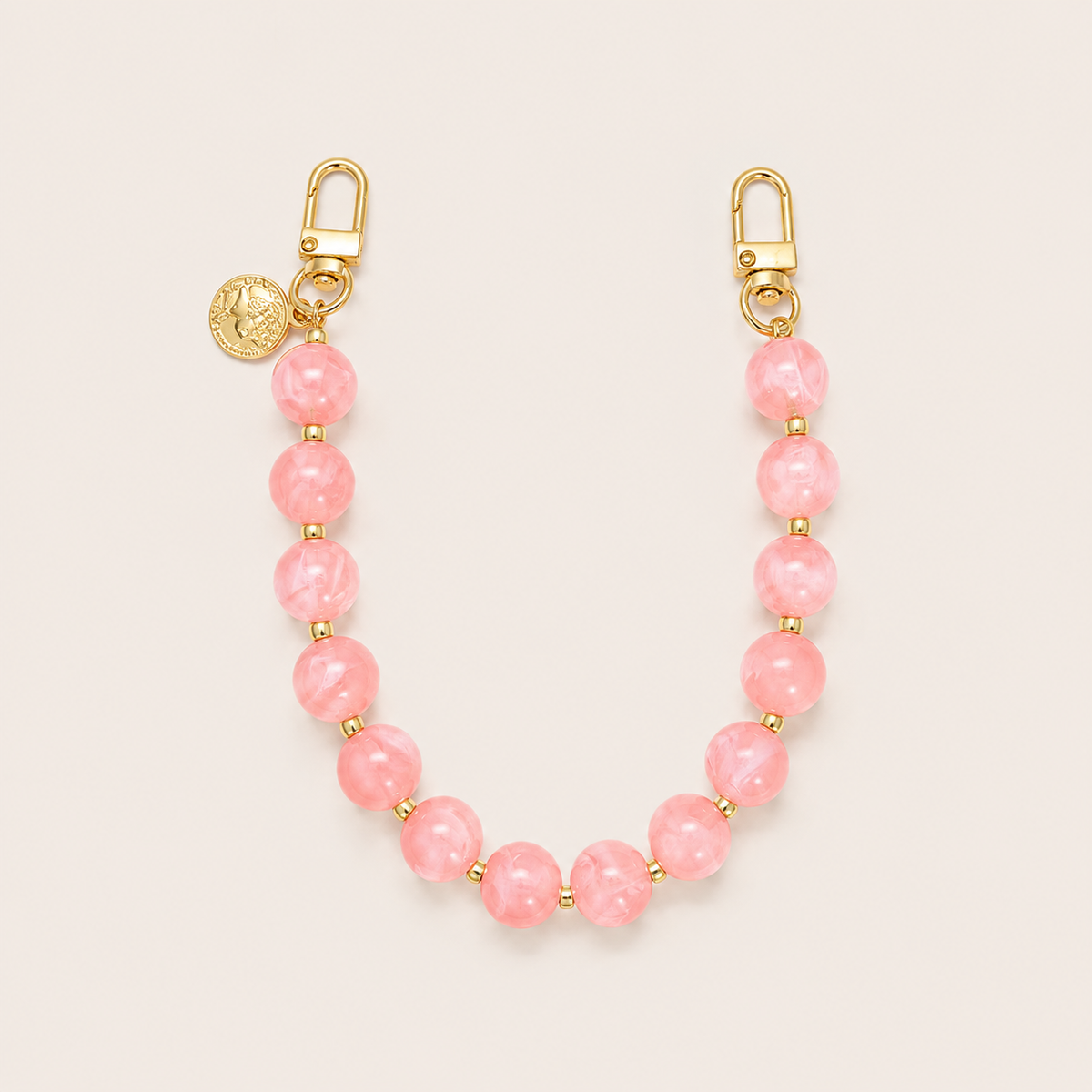 The Sable PHONE CHAIN in soft pink rose-quartz-effect beads with gold-tone spacers, clasps, and a coin charm.