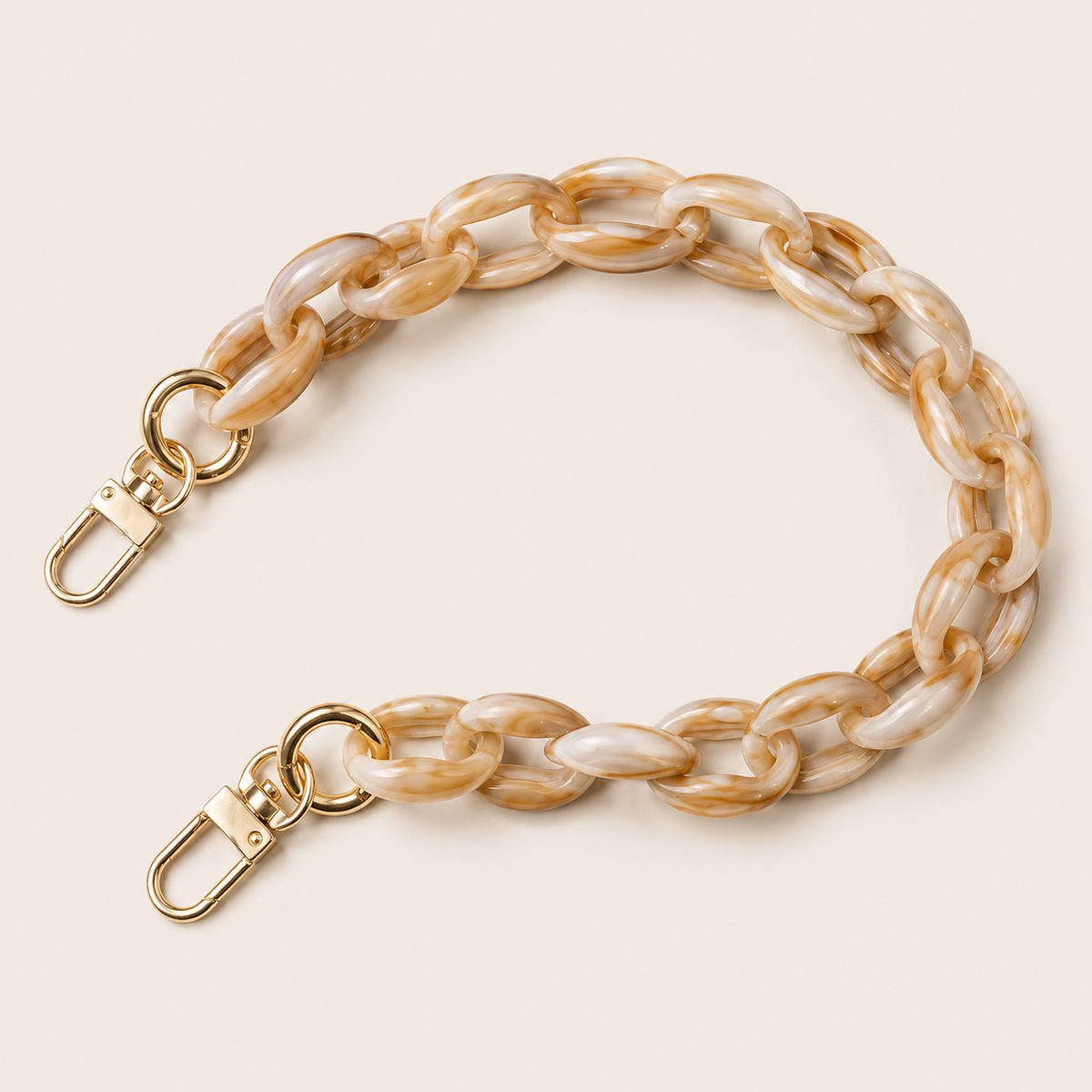 The Ember SHORT PHONE CHAIN in marbled cream-and-tan acrylic with gold-tone lobster clasp ends, curved on a beige background.