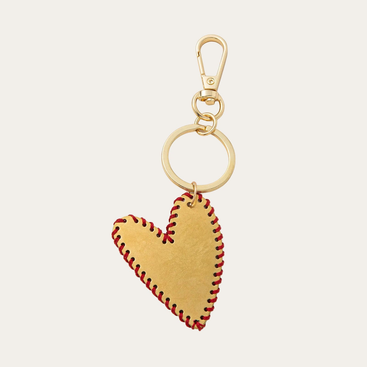Gold-tone brass heart bag charm with a stitched edge detail, on a swivel hook and keyring.