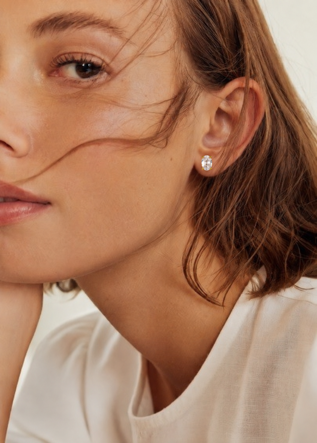 Ovalie EARRINGS stud with an oval clear stone, worn by a model with windswept hair and a white T-shirt.