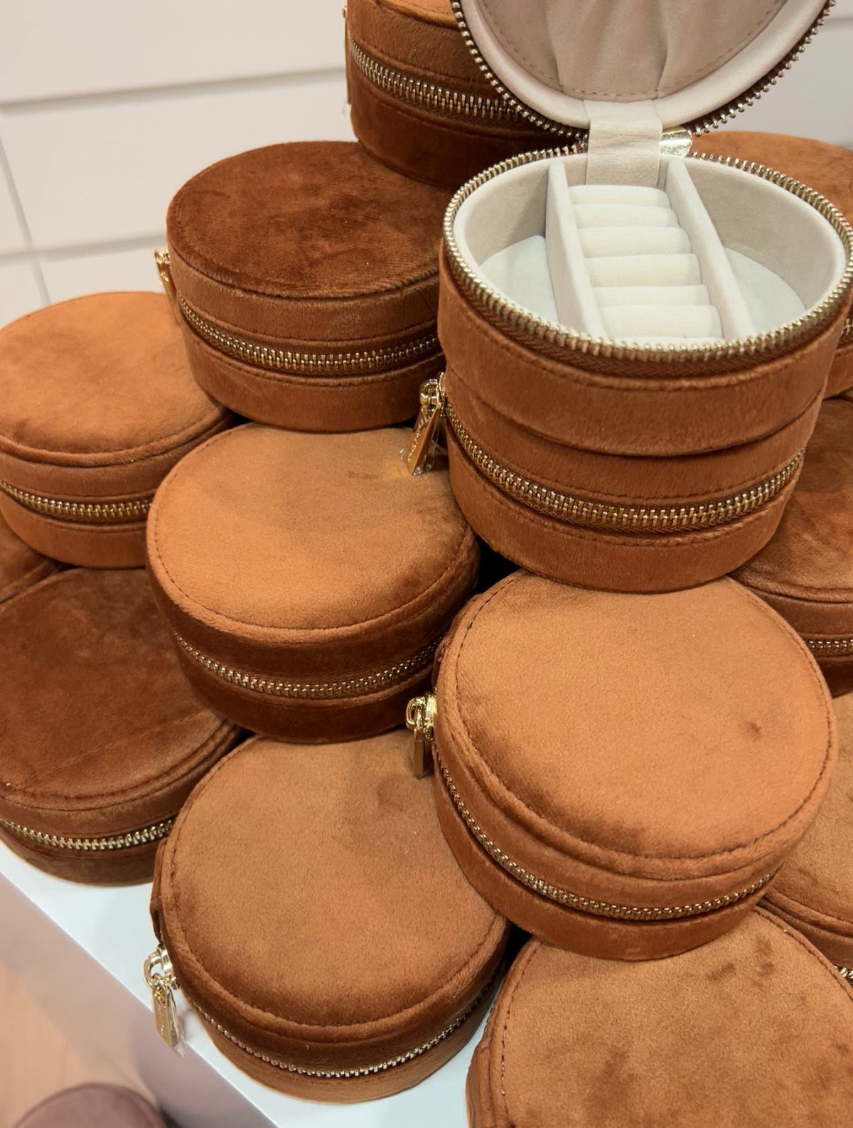 Pile of cognac velvet Travel Jewelry CASE pouches with gold zips, one open to show the cream ring roll inside.